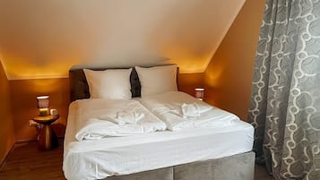 A bedroom with a bed, bedside tables, and curtains.
