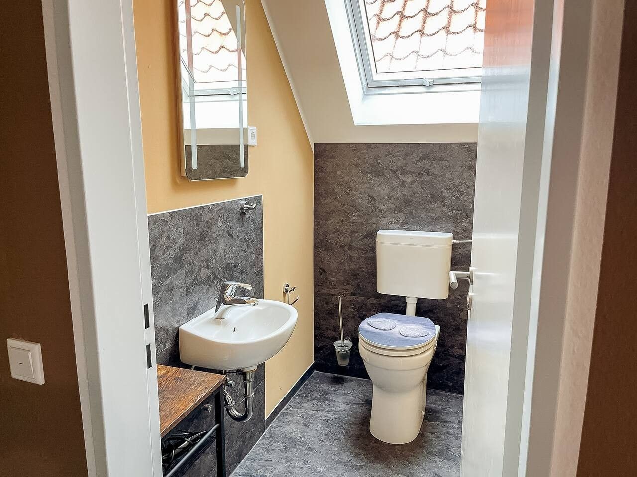 Ein kleines Badezimmer mit Oberlicht, Waschbecken und Toilette.