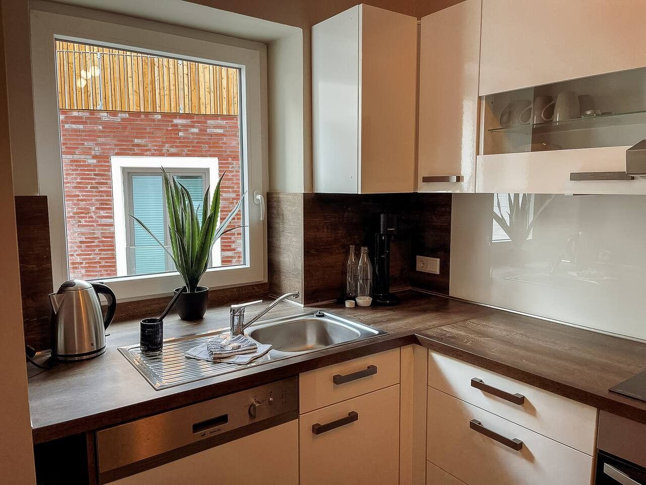 Eine moderne Küche mit Fenster, Spüle, Schränken und Arbeitsplatte.