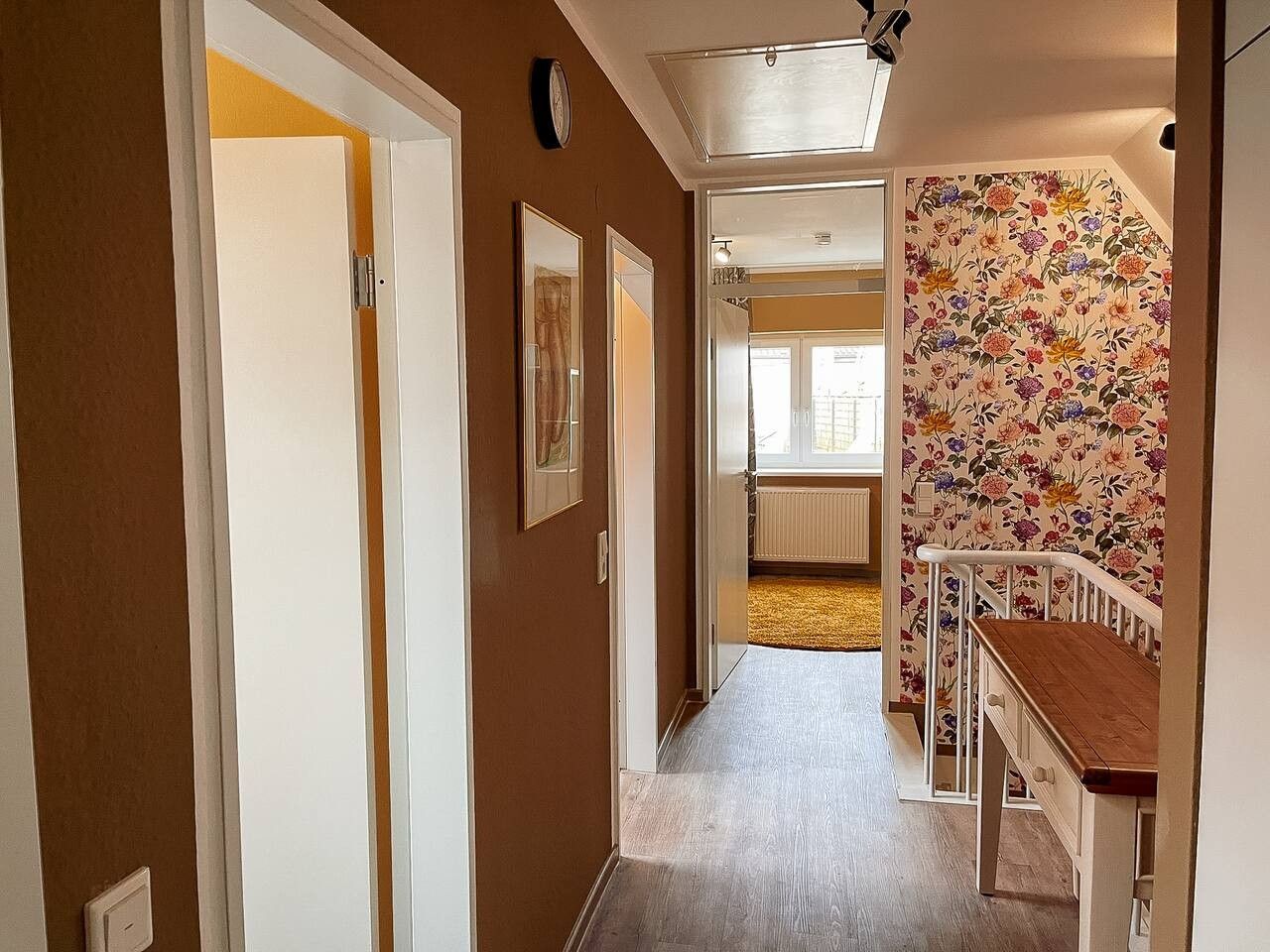 Un couloir avec un banc en bois, un radiateur et une porte donnant sur une autre pièce.