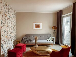 A living room with a sofa, a coffee table, and a floor lamp. - Apt. Prinz Maximilian | Zentrum | Zimmerprinzen (Oldenburg)
