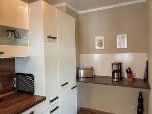 A modern kitchen with white cabinets, a coffee maker, a toaster, and a knife block.