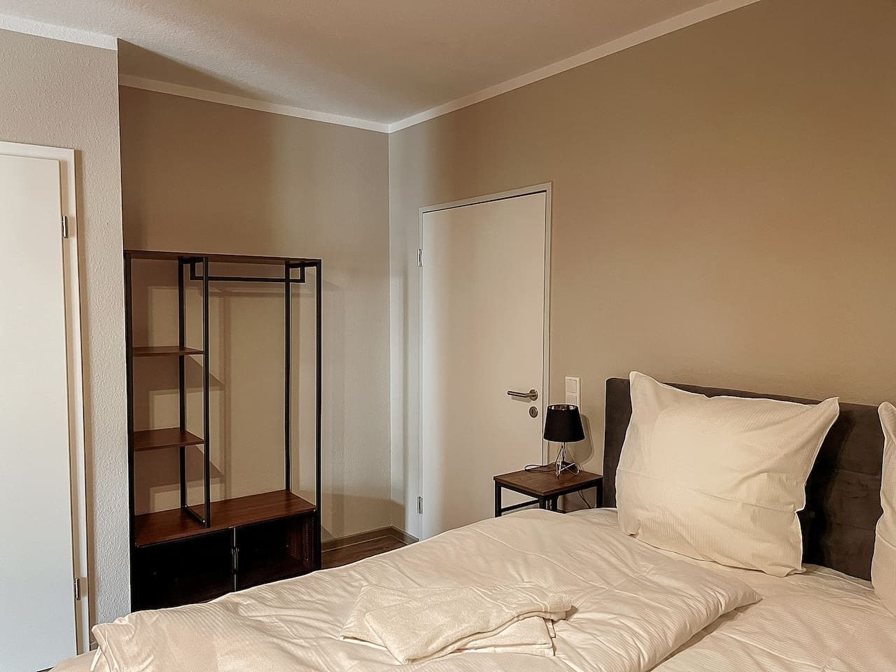 Une chambre à coucher avec un lit, une table de chevet, un miroir et une armoire.
