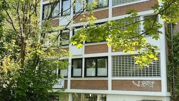 Un edificio a più piani con facciata in mattoni, ampie finestre e una bicicletta parcheggiata davanti.