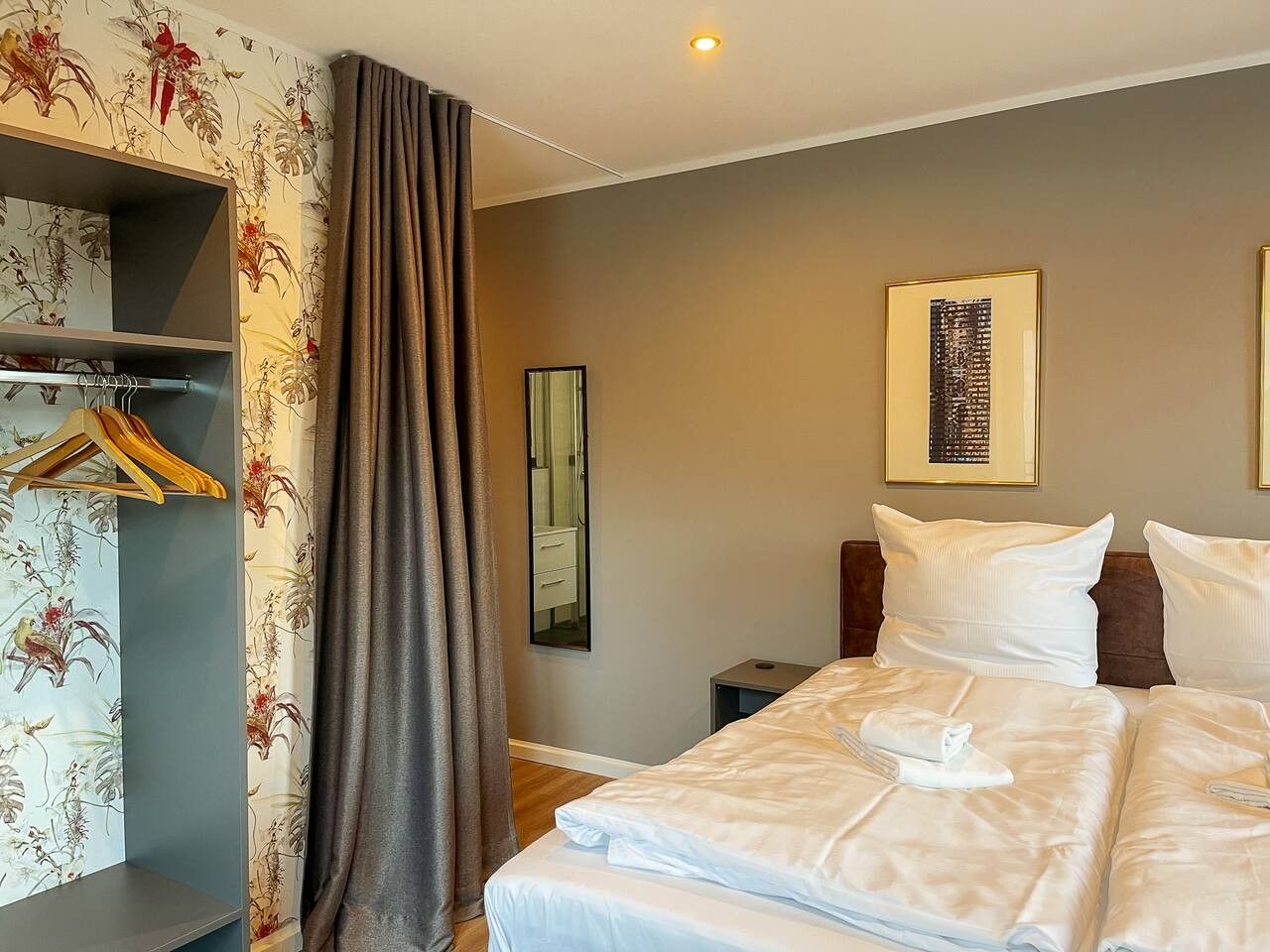 Een hotelkamer met een bed, een kledingkast, een spiegel en een kunstwerk in een lijst aan de muur.