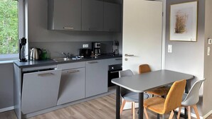 Cozinha moderna com armários cinzas, cafeteira e área de refeições com duas cadeiras.