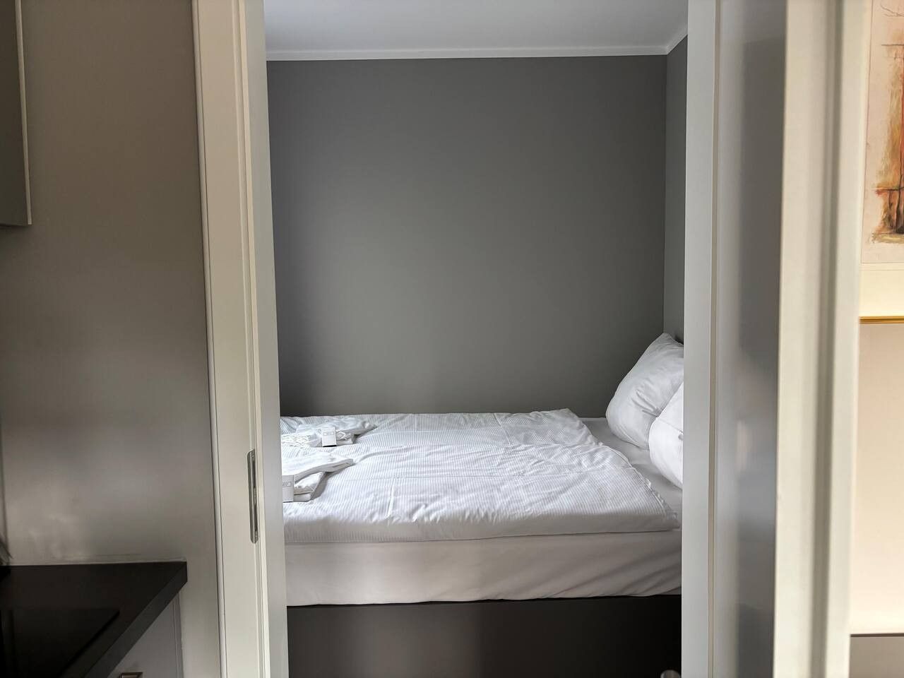 Ein kleines, abgeschlossenes Schlafzimmer mit einem Bett, Kissen und einem Nachttisch.