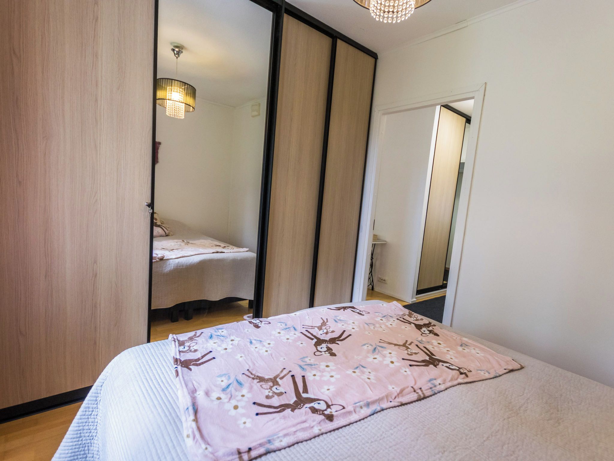 A bedroom with a bed, a mirror, and a wardrobe.