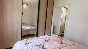 A bedroom with a bed, a mirror, and a wardrobe.
