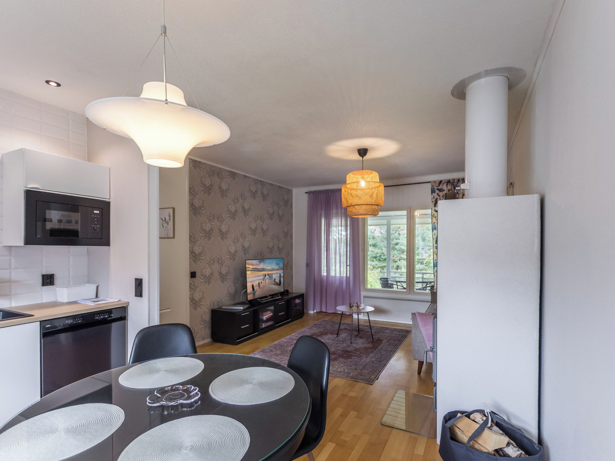 A modern kitchen with a microwave, dishwasher, and dining area with a round table and chairs.