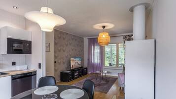 A modern kitchen with a microwave, dishwasher, and dining area with a round table and chairs.