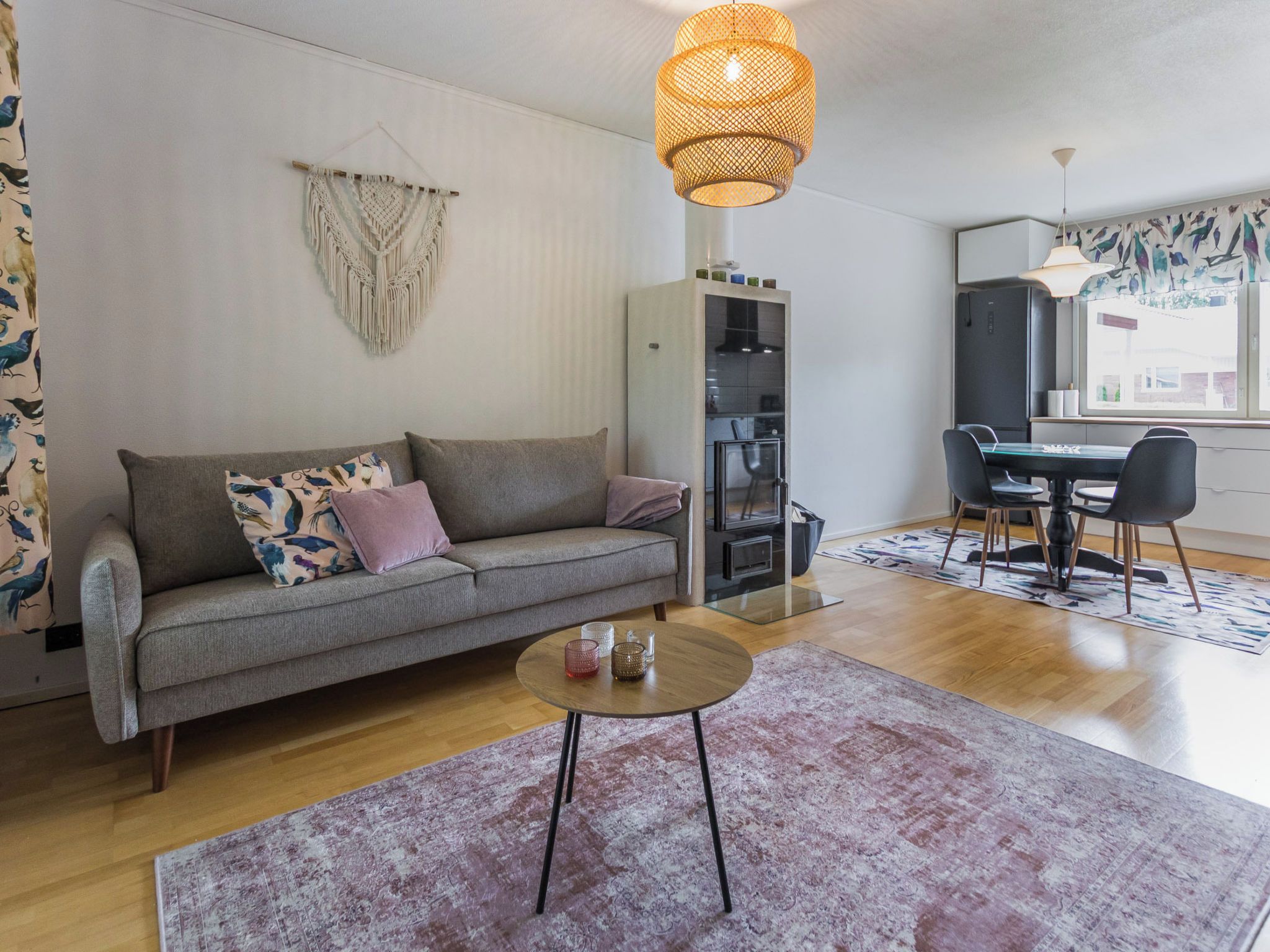 Un salon moderne avec un canapé gris, une table basse ronde et un coin repas comprenant une table et des chaises en verre.