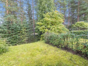 A forested area with a grassy foreground and a metal fence. - Artunkuja by Interhome (Sotkamo)