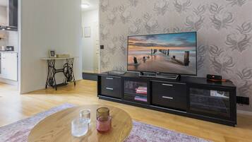 A modern living room with a flat-screen TV, a wooden coffee table, and a patterned rug.