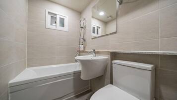 A bathroom with a bathtub, sink, toilet, and a mirror.