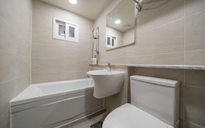 Ein Badezimmer mit Badewanne, Waschbecken, Toilette und Spiegel.