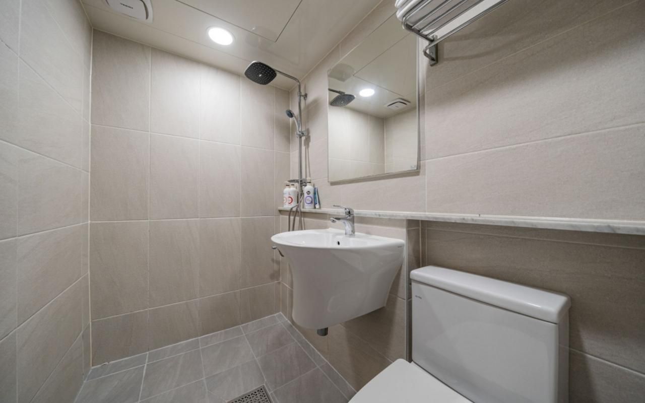 Un baño con lavamanos, espejo e inodoro.