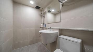 Un baño con lavamanos, espejo e inodoro.