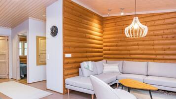 A modern living room with a wooden wall, a sofa, a chair, and a hanging light fixture.