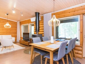 A modern log cabin interior with a dining area, seating, a television, and a fireplace. - Mäkrä 3 by Interhome (Lieksa)