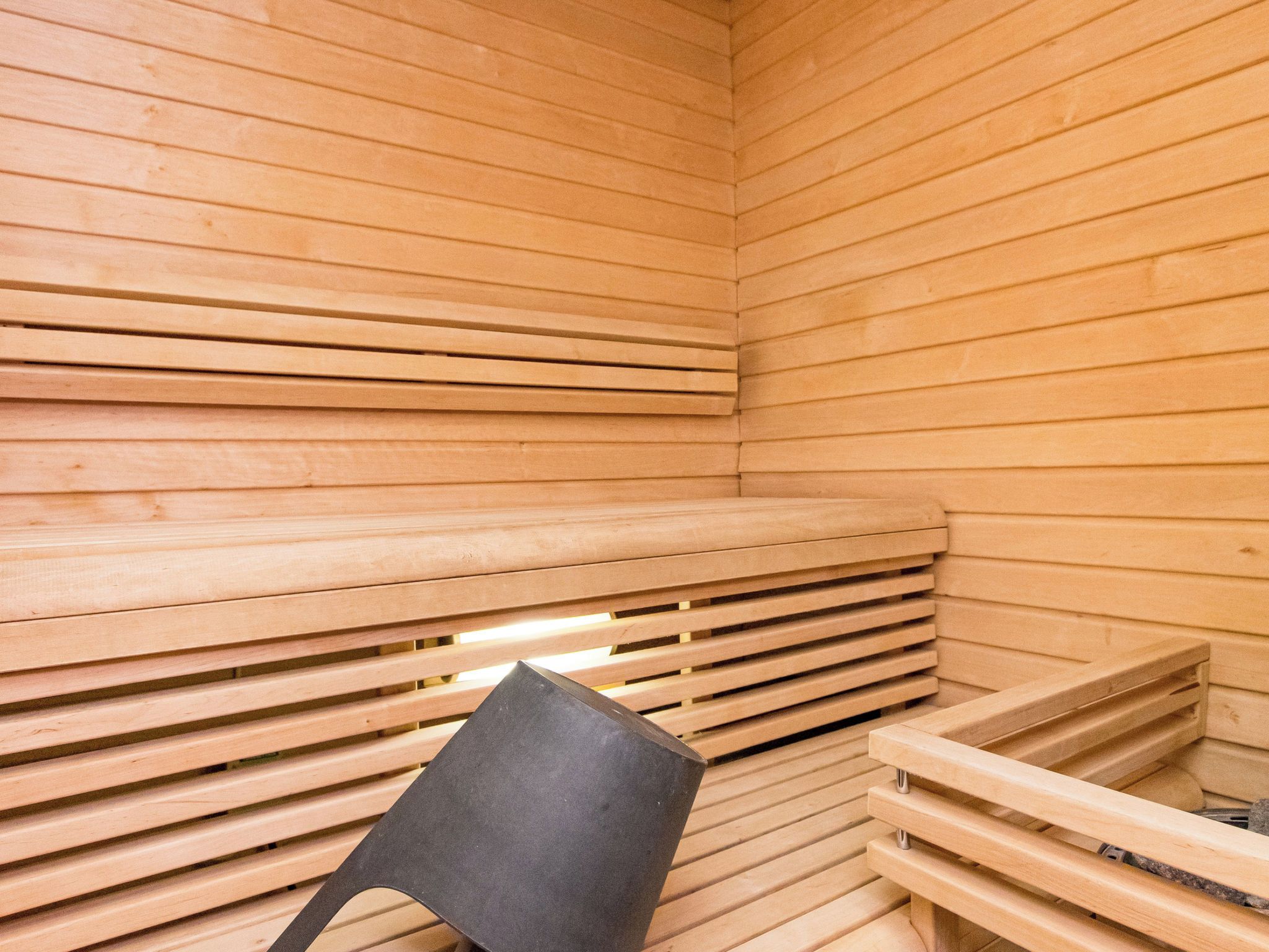 A sauna with wooden slats and a black chair.