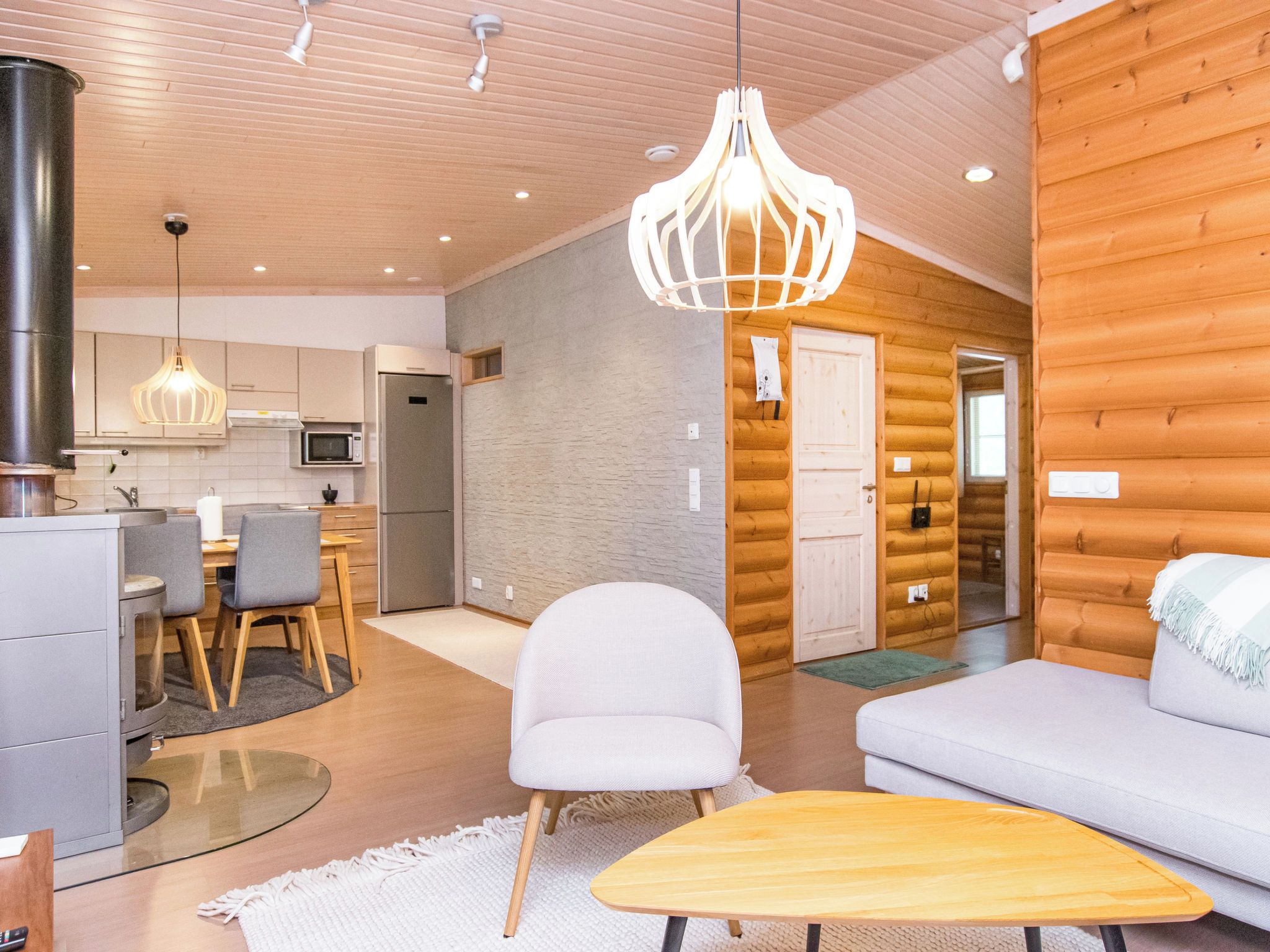 A modern log cabin interior with a dining area, kitchen, and living room.