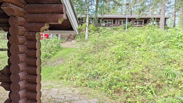 A rustic cabin with a stone-paved entrance and a dense forest backdrop.
