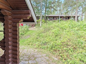 Una cabana rústica amb un vestíbul empedrat i un bosc dens al fons.