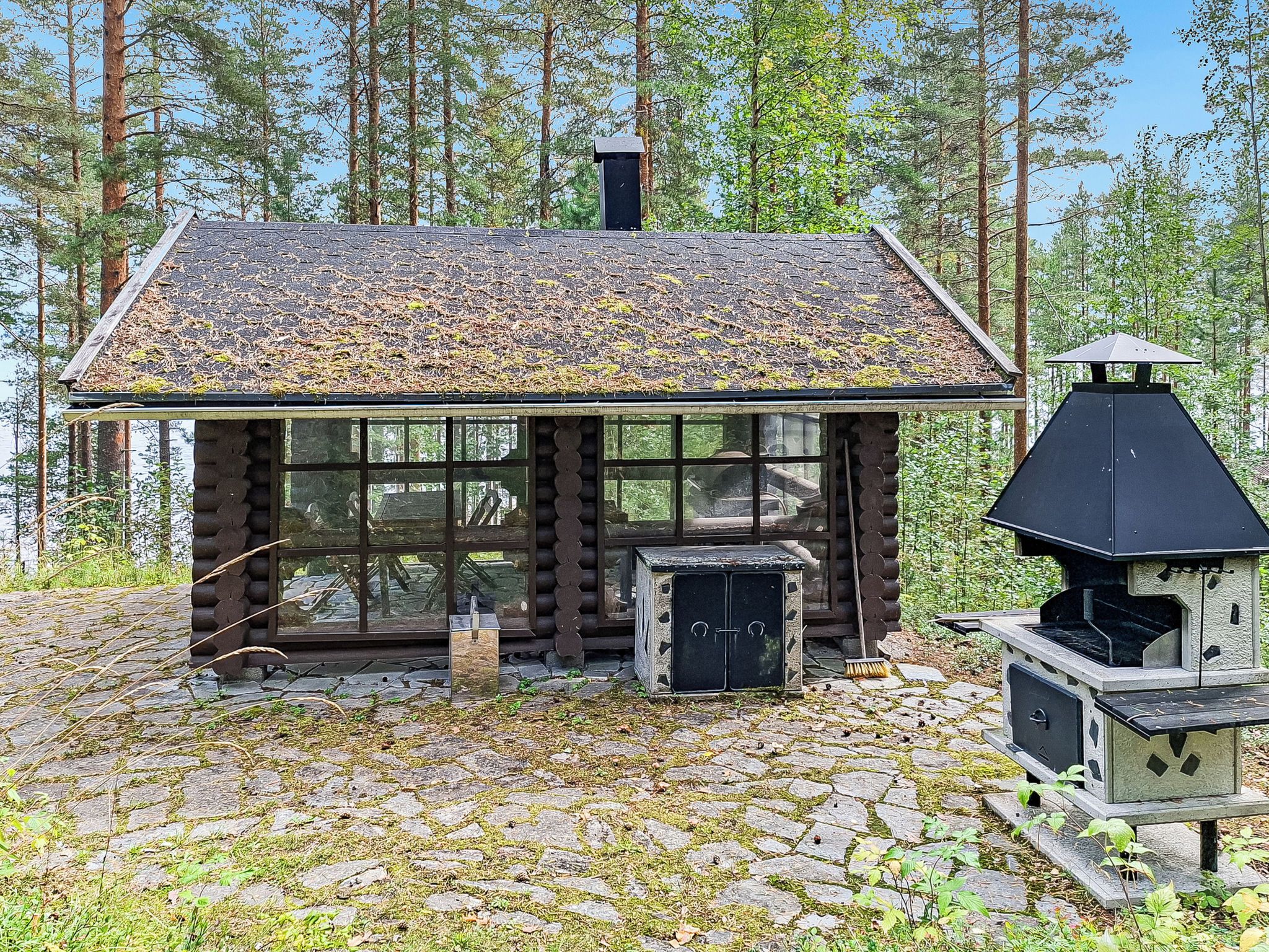 A rustic cabin with a log exterior, a chimney, and a wood-burning stove.