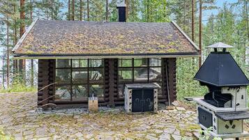 A rustic cabin with a log exterior, a chimney, and a wood-burning stove.