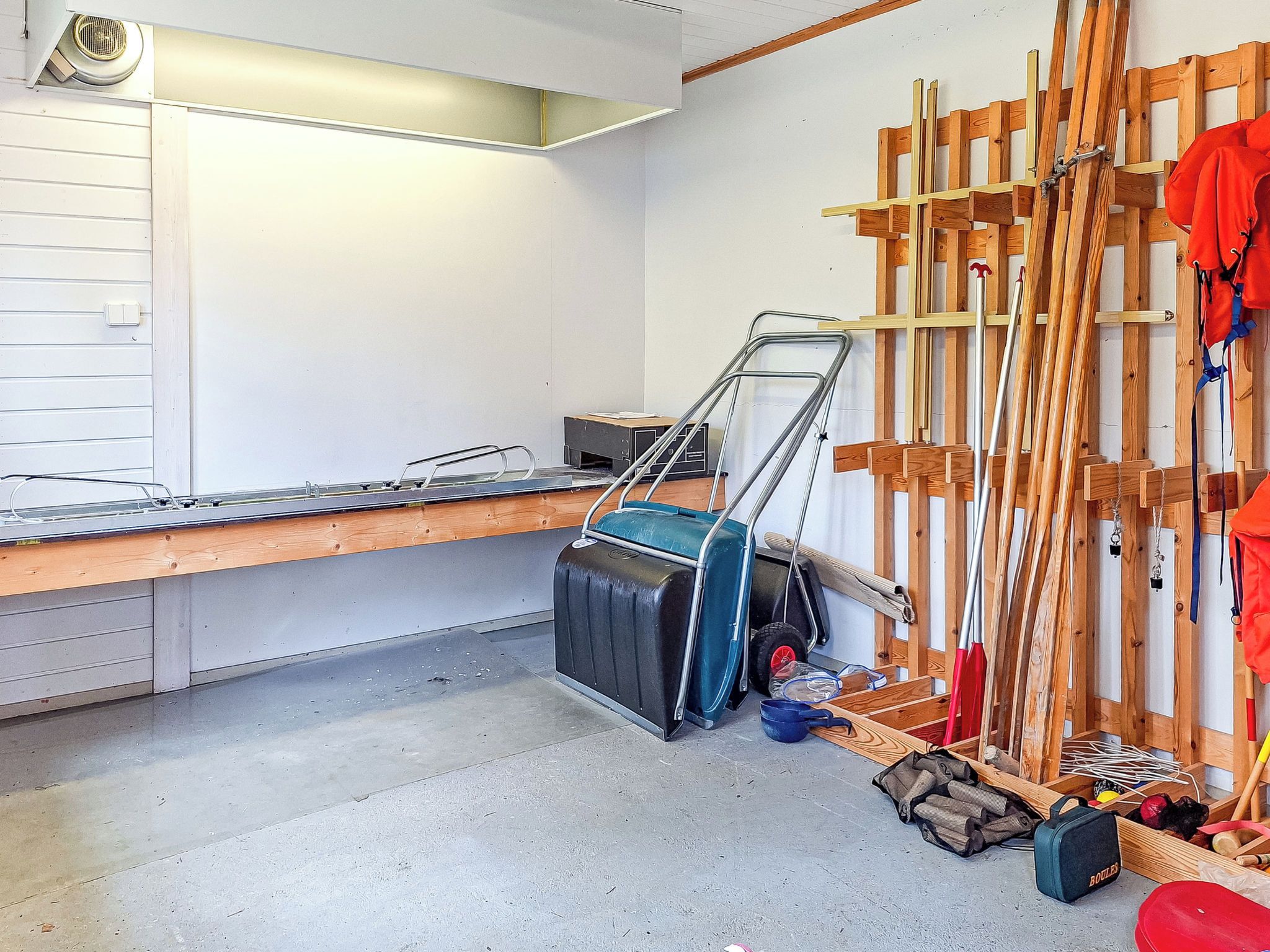A room with a wooden workbench, a suitcase, and various tools.