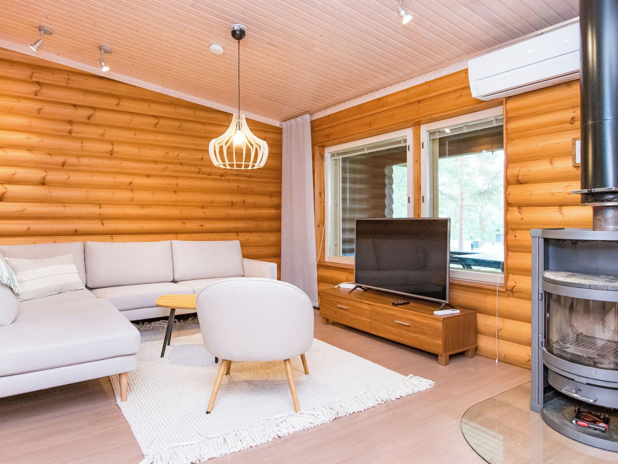 Intérieur moderne d’une cabane en rondins, avec un canapé, un téléviseur et une cheminée.