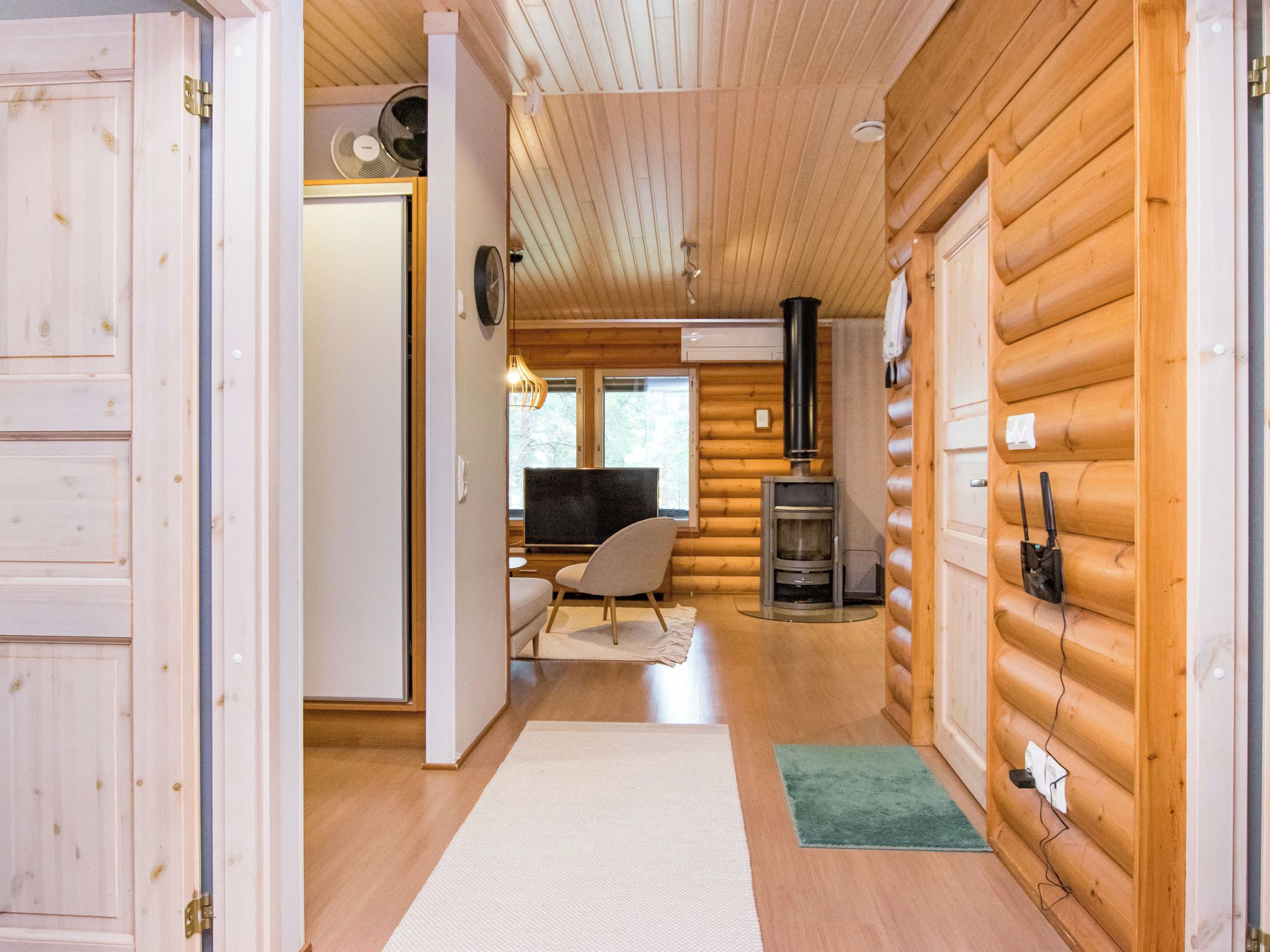 A log cabin interior with a wooden floor, a television, a fireplace, and a chair.