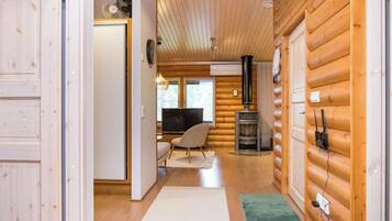 A log cabin interior with a wooden floor, a television, a fireplace, and a chair.
