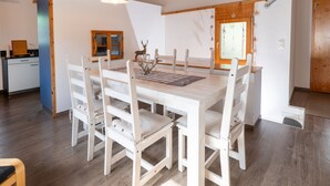 Een eetgedeelte met een houten tafel en stoelen, een hanglamp en een raam met uitzicht.