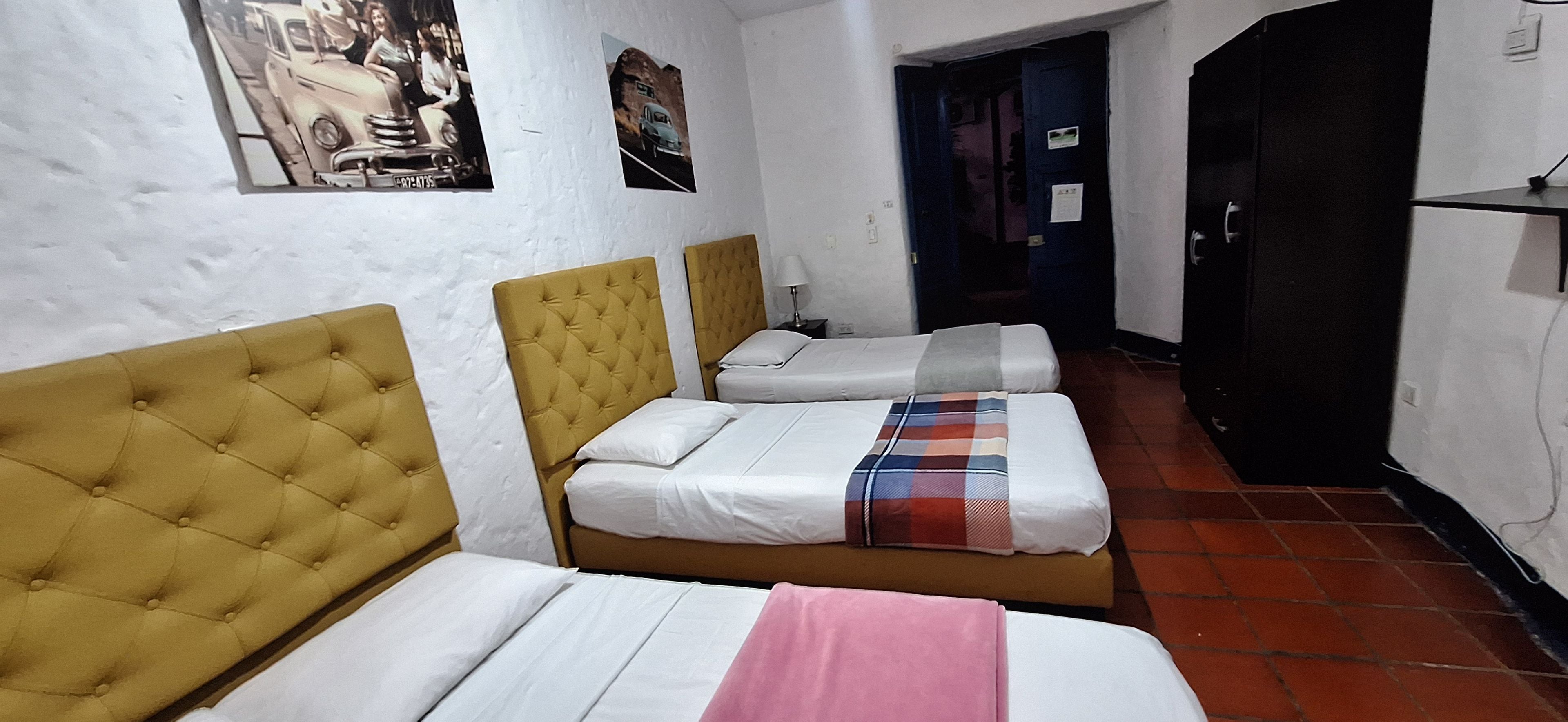 Una habitación de hotel con tres camas, un armario y una puerta.