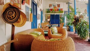 Un interno accogliente con mobili in vimini, una porta blu e un cartello con la scritta 'YO LOVE ANTIOQUIA'.