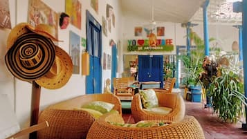 Een gezellig interieur met rieten meubels, een blauwe deur en een bord waarop staat 'YO LOVE ANTIOQUIA'.