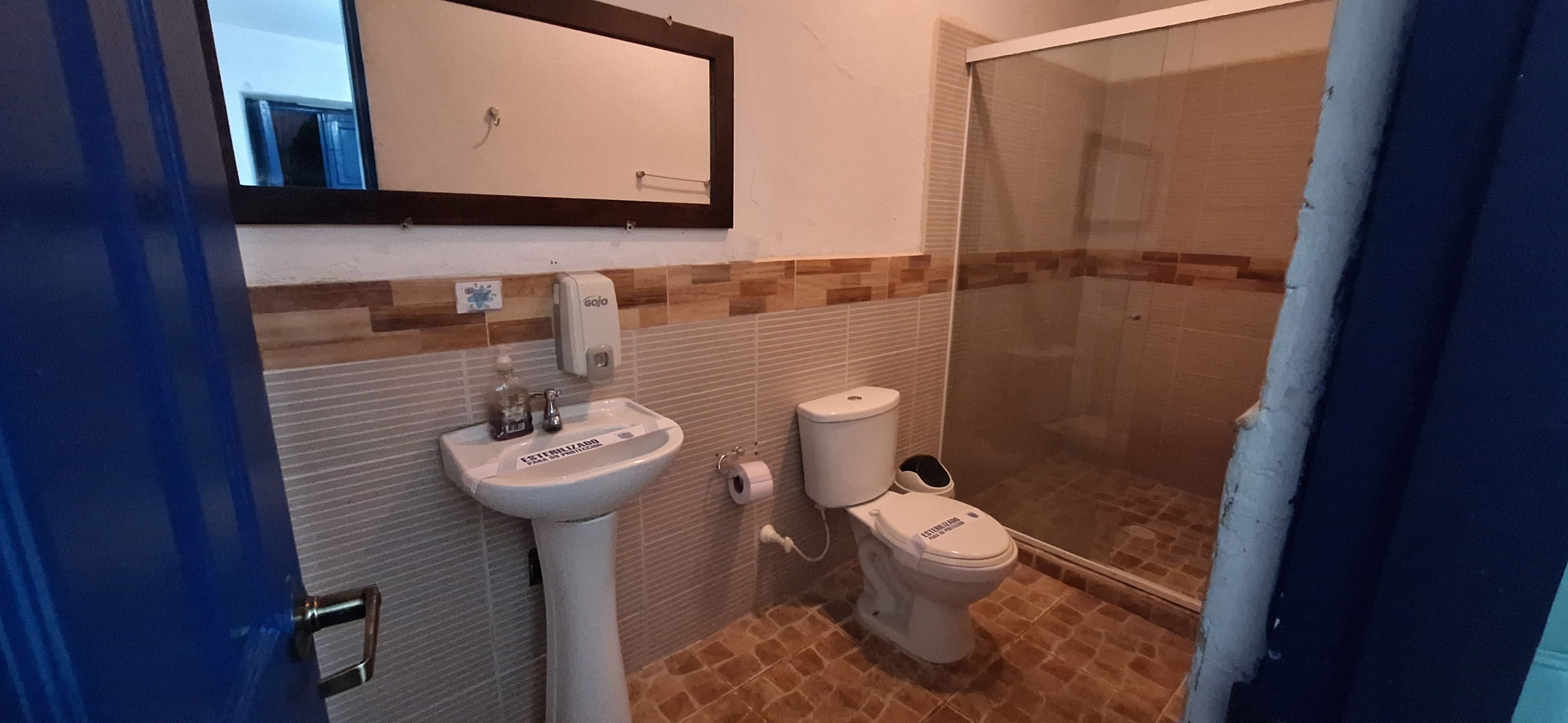 Casa de banho com lavatório, sanita e cabine de duche em vidro.