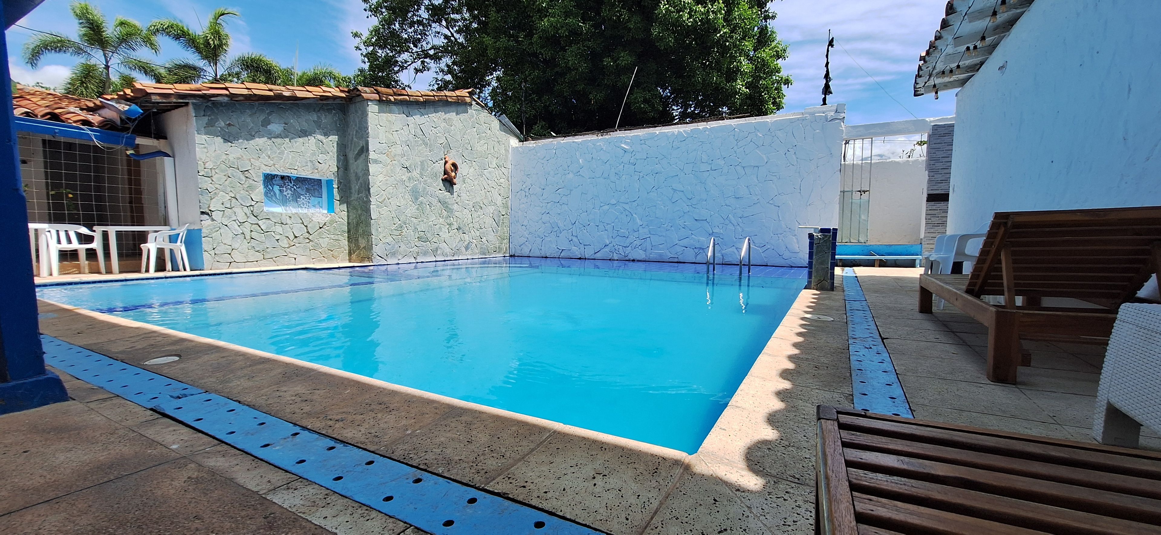 Une piscine avec un mur en pierre et une terrasse en bois.