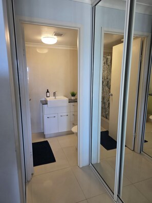 Ein modernes Badezimmer mit Waschbecken, Toilette und Duschbereich in Weiß.