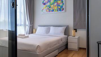 A hotel room with a bed, a nightstand, a lamp, and a painting on the wall.