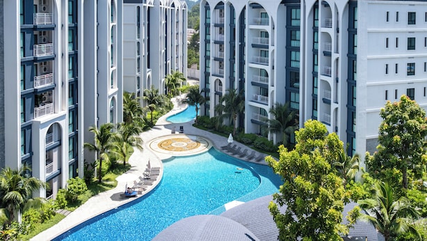 Un resort con edifici a più piani, una piscina centrale e palme circostanti.