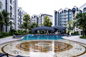 Um resort com piscina central, espreguiçadeiras e um design de mosaico circular único.