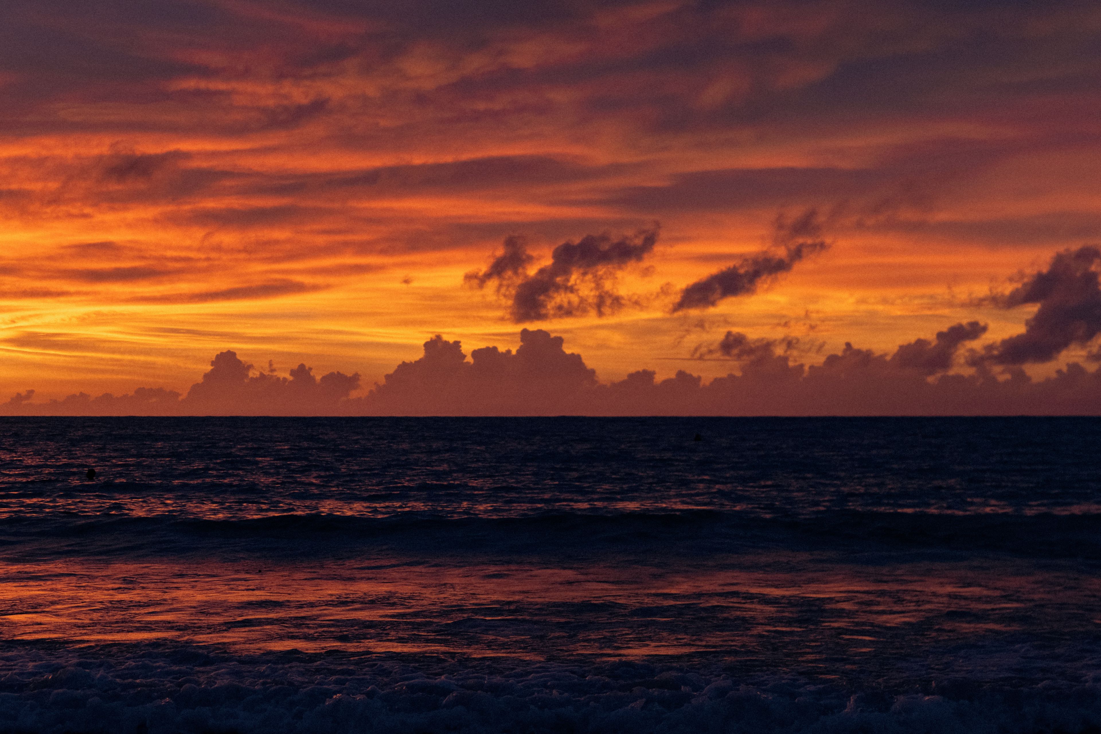 A sunset over a body of water with clouds in the sky.