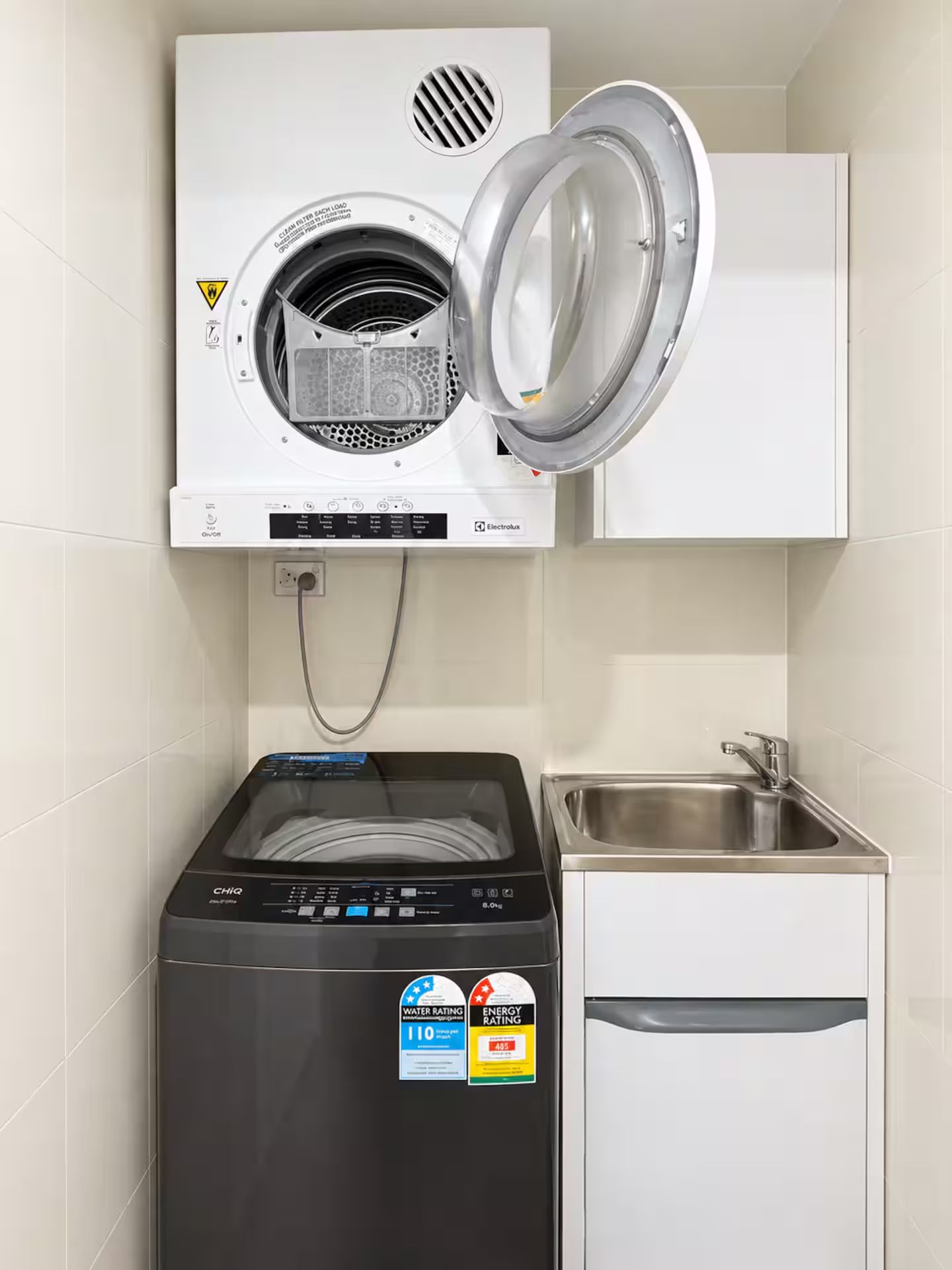 A compact washer and dryer unit with a control panel, a built-in sink, and a small cabinet.