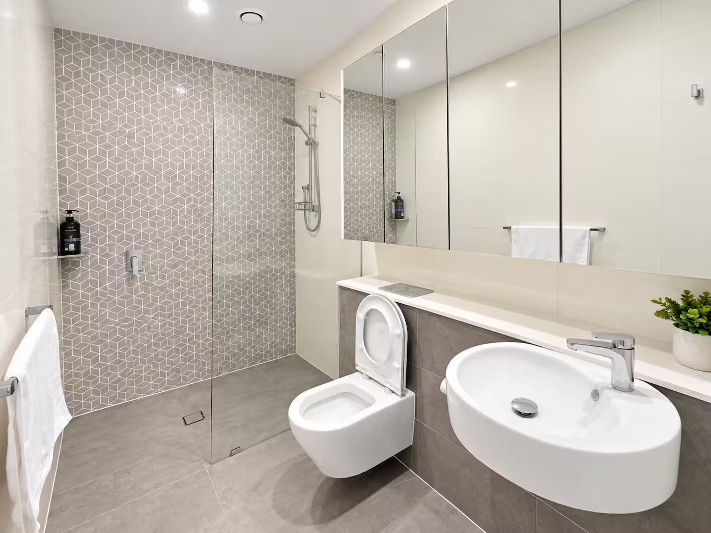 A modern bathroom with a glass-enclosed shower, a toilet, and a sink.