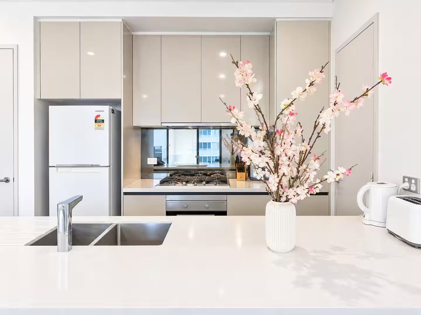 A modern kitchen with a built-in stove, a refrigerator, and a sink.