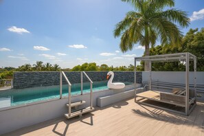 Ein Pool auf dem Dach mit einer Schwan-Luftmatratze, einer Holzterrasse und einer Pergola mit Liege.