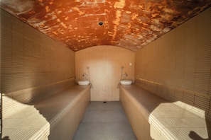 Un baño estrecho con azulejos, dos lavamanos y techo inclinado.